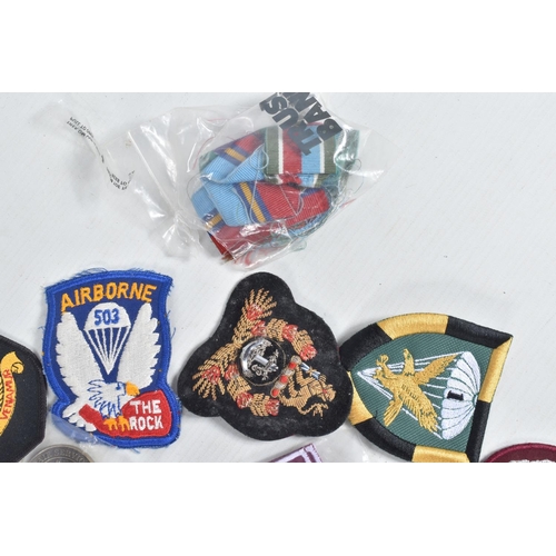 287 - PLASTIC BOX CONTAING NUMBER OF MILITARY RELATED CAP DEVICES, SHOULDER AND ARM PATCHES etc many from ... 