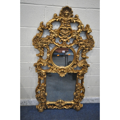 1252 - A MODERN ORNATE GILT FRAME WALL MIRROR, with scrolled and foliate details, a circular pane, above a ... 