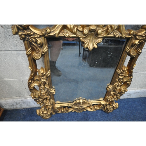 1252 - A MODERN ORNATE GILT FRAME WALL MIRROR, with scrolled and foliate details, a circular pane, above a ... 