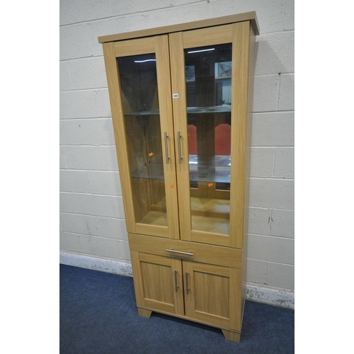 1255 - A MODERN OAK DISPLAY CABINET, the double glass doors, enclosing two glass shelves and a mirror back,... 