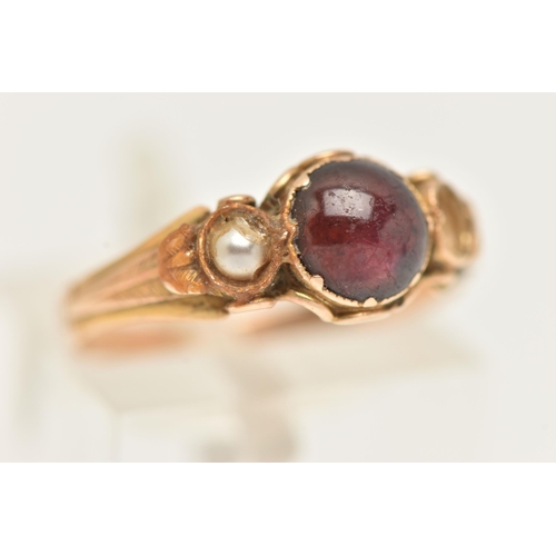 23 - A YELLOW METAL GEM SET RING, AF set with a central garnet cabochon, collet set and flanked with a sp... 