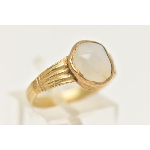 32 - A YELLOW METAL QUARTZ RING, set with a quartz cabochon stone, rough collet set to textured shoulders... 