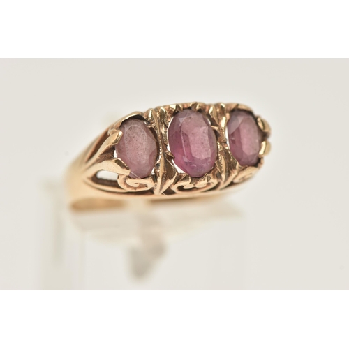 43 - A 9CT GOLD THREE STONE RING, set with three oval cut pink stones assesed as paste, to the scrolling ... 