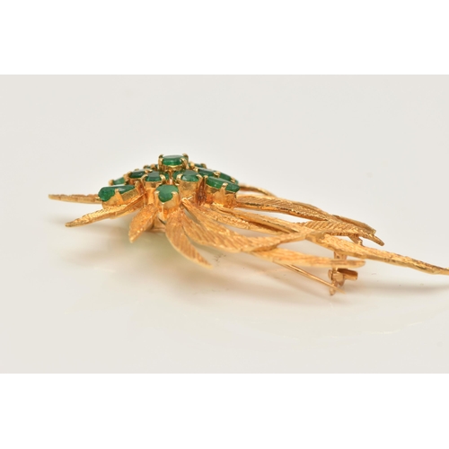 45 - A YELLOW METAL EMERALD SET SPRAY BROOCH, textured spray of leaves, set with a cluster of circular cu... 