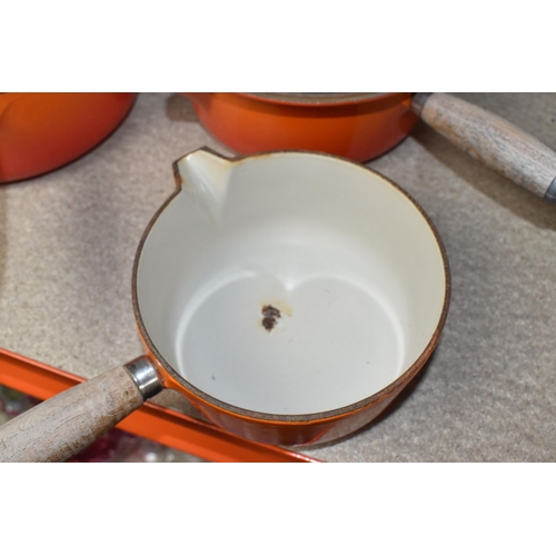 361 - FOUR LE CREUSET CAST IRON SAUCEPANS, in orange enamel with pouring lips and wooden handles, diameter... 