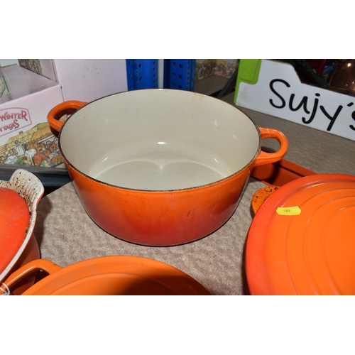 409 - LE CREUSET CAST IRON SAUCEPANS/ CASSEROLE POTS AND CRUET SET, in orange enamel outer finish and crea... 