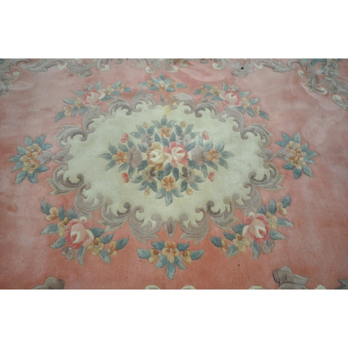 1204 - A LARGE PINK GROUND CHINESE WOOLLEN RUG, with a central medallion, repeating foliate patterns, unite... 