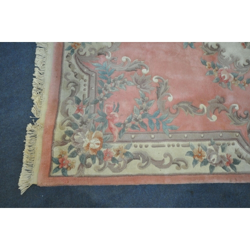 1204 - A LARGE PINK GROUND CHINESE WOOLLEN RUG, with a central medallion, repeating foliate patterns, unite... 