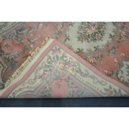 1204 - A LARGE PINK GROUND CHINESE WOOLLEN RUG, with a central medallion, repeating foliate patterns, unite... 