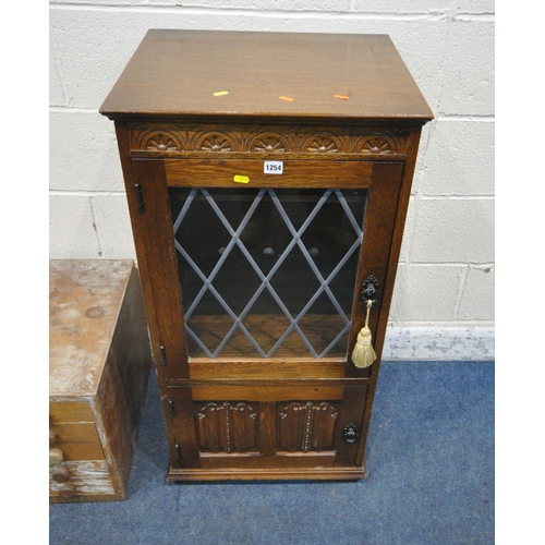 1254 - A LATE 20TH CENTURY OAK MEDIA CABINET, with a hinged lid, single lead glazed door, above a linenfold... 