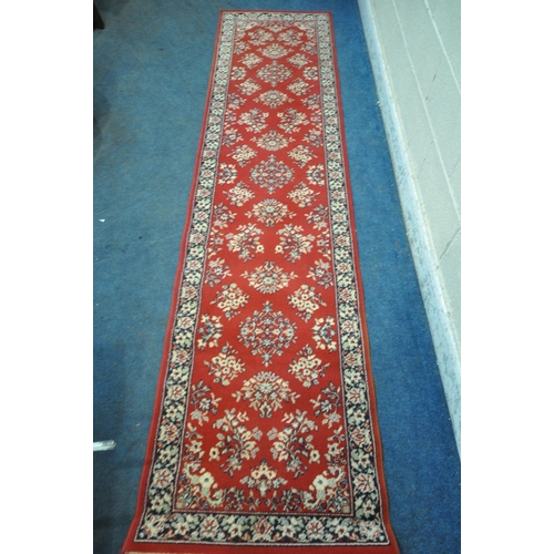 1321 - A RED GROUND RECTANGULAR CARPET RUNNER, with repeating patterns, surrounded by a multi-strap border,... 