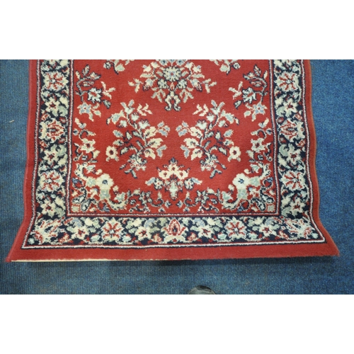 1321 - A RED GROUND RECTANGULAR CARPET RUNNER, with repeating patterns, surrounded by a multi-strap border,... 