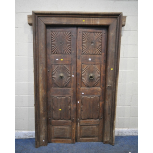 1330 - A HEAVY CARVED EASTERN HARDWOOD DOUBLE DOORS, within a moulded frame, the doors with reeded rosette ... 