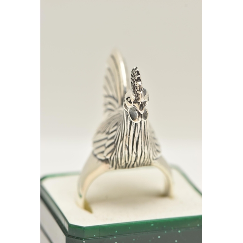 70 - A LARGE WHITE METAL RING, designed as a chicken, leading on to a tapered shank, approximate height 2... 