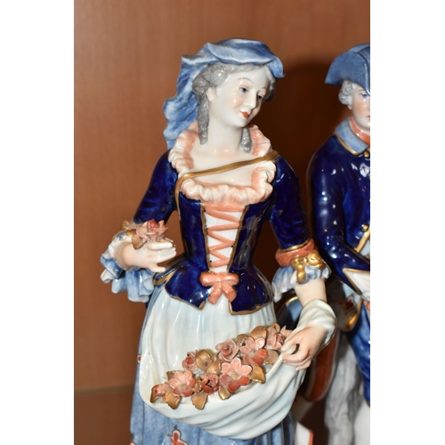 316 - A PAIR OF RUDOLSTADT VOLKSTEDT FIGURINES comprising a  female figurine carrying flowers in her dress... 