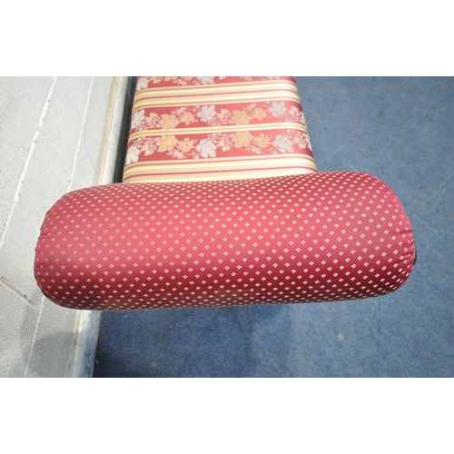 164 - A REPRODUCTION ITALIAN STYLE WINDOW SEAT, with scrolled armrests, raised on winged padded feet, stri... 