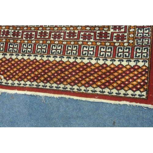 190 - A RED GROUND RUG, with twenty-four central medallions, surrounded by a multi-strap border, length 18... 