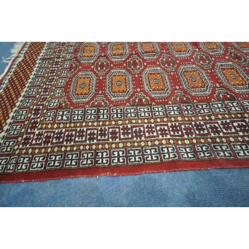 190 - A RED GROUND RUG, with twenty-four central medallions, surrounded by a multi-strap border, length 18... 