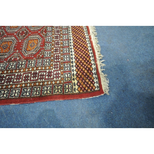 190 - A RED GROUND RUG, with twenty-four central medallions, surrounded by a multi-strap border, length 18... 