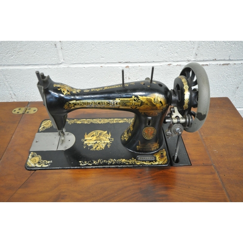 219 - A 20TH CENTURY TREADLE SINGER SEWING MACHINE, serial number p461577, the hinged surface enclosing th... 