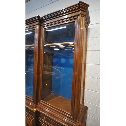 221 - A 20TH CENTURY MAHOGANY AND WALNUT BREAKFRONT BOOKCASE, fitted with four bevelled glass doors, atop ... 