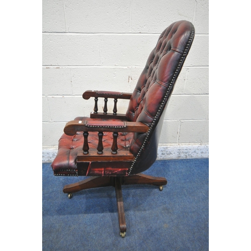 156 - AN OXBLOOD BUTTONED SWIVEL OFFICE CHAIR, with spindled armrests, on brass castors, width 60cm x dept... 