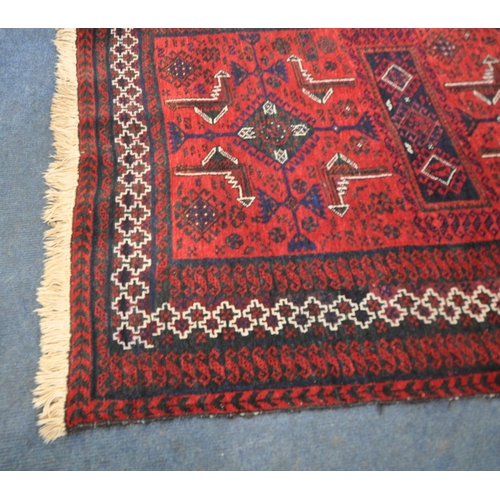 187 - A RED GROUND RECTANGULAR RUG, with repeating geometric patterns, surrounded by a multi-strap border,... 