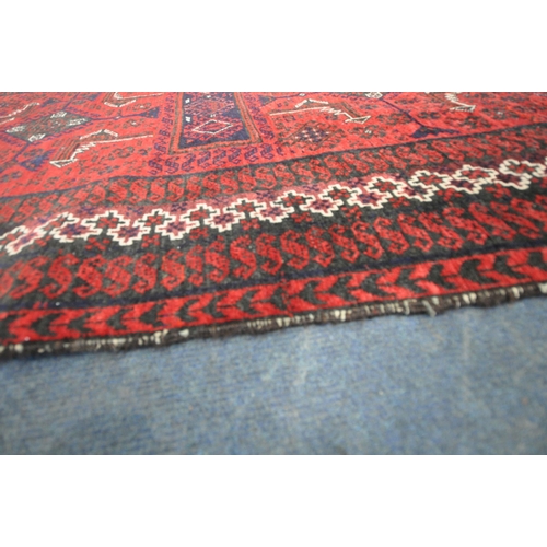 187 - A RED GROUND RECTANGULAR RUG, with repeating geometric patterns, surrounded by a multi-strap border,... 