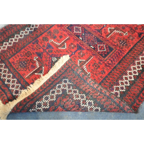 187 - A RED GROUND RECTANGULAR RUG, with repeating geometric patterns, surrounded by a multi-strap border,... 