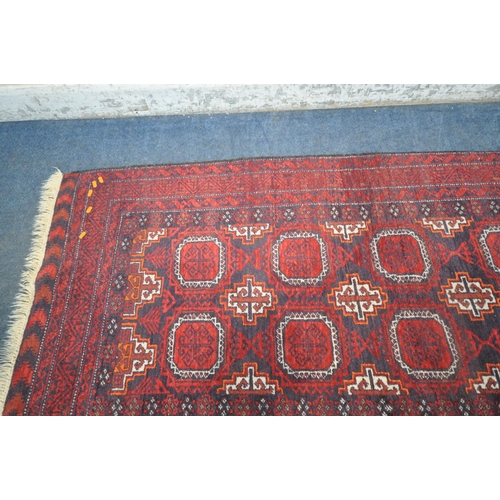 188 - A RED GROUND RECTANGULAR RUG, with eight medallions, repeating geometric patterns, surrounded by a m... 