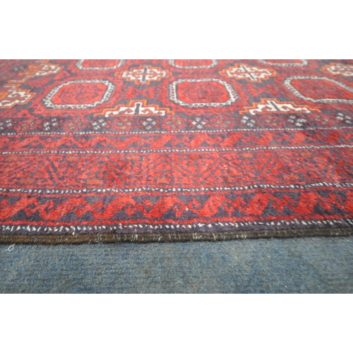 188 - A RED GROUND RECTANGULAR RUG, with eight medallions, repeating geometric patterns, surrounded by a m... 