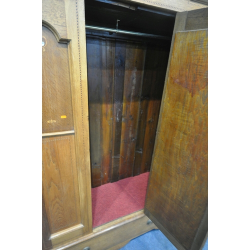 208 - A 20TH CENTURY OAK WARDROBE, with an arched cornice, an oval mirrored door, above a single drawer, w... 