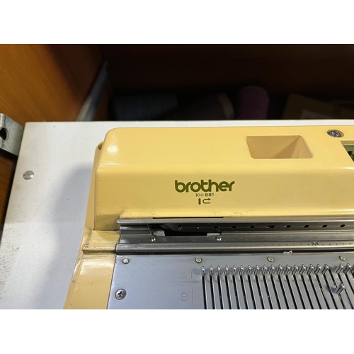 82 - A BROTHER KH-881 KNITTING MACHINE IN A CHERRYWOOD EFFECT CABINET with rolling drawer, accessories an... 