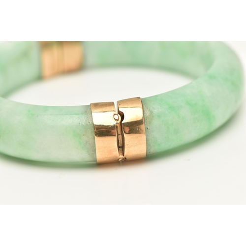 420 - A JADE BANGLE, a dyed jade bangle with yellow metal hinge and clasp fittings, approximate width 15mm... 