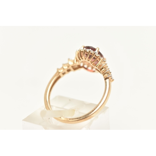 445 - A 9CT GOLD CLUSTER RING, of an oval form, set with an oval cut pinkish stone assessed as tourmaline,... 