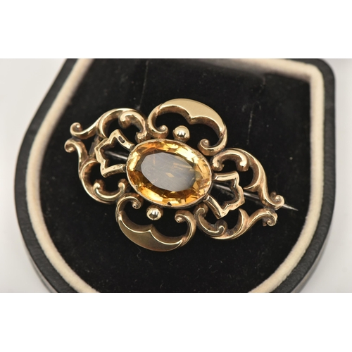 568 - A YELLOW METAL CITRINE BROOCH, open work brooch set with a central oval cut Citrine, collet set to t... 