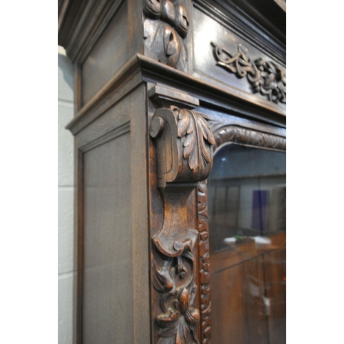 154 - A 20TH CENTURY OAK BOOKCASE, with intricate carved details, the double glazed doors enclosing three ... 