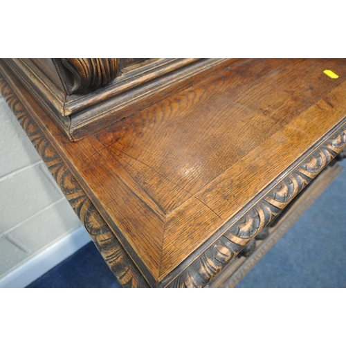 154 - A 20TH CENTURY OAK BOOKCASE, with intricate carved details, the double glazed doors enclosing three ... 