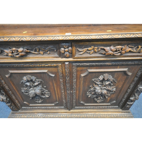 154 - A 20TH CENTURY OAK BOOKCASE, with intricate carved details, the double glazed doors enclosing three ... 