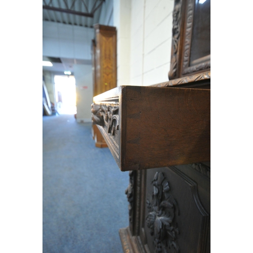 154 - A 20TH CENTURY OAK BOOKCASE, with intricate carved details, the double glazed doors enclosing three ... 