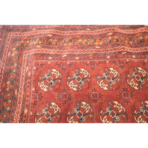 201 - A IRANIAN RED WOOLEN TEKKE RUG, with twelve central medallions, surrounded by a multi-strap border, ... 