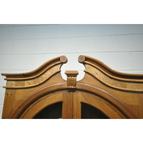 248 - A 20TH CENTURY PINE BOOKCASE, with twin swan neck pediment, the arched double doors enclosing two sh... 