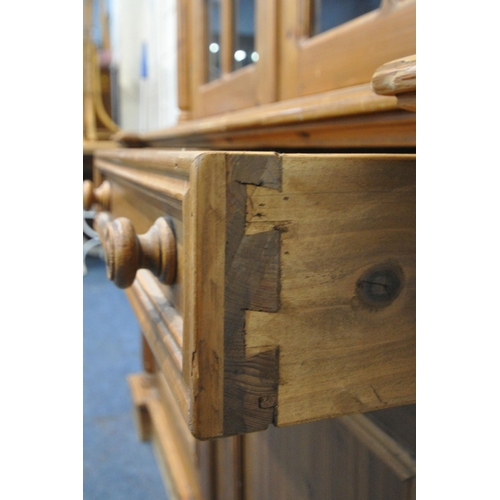 248 - A 20TH CENTURY PINE BOOKCASE, with twin swan neck pediment, the arched double doors enclosing two sh... 