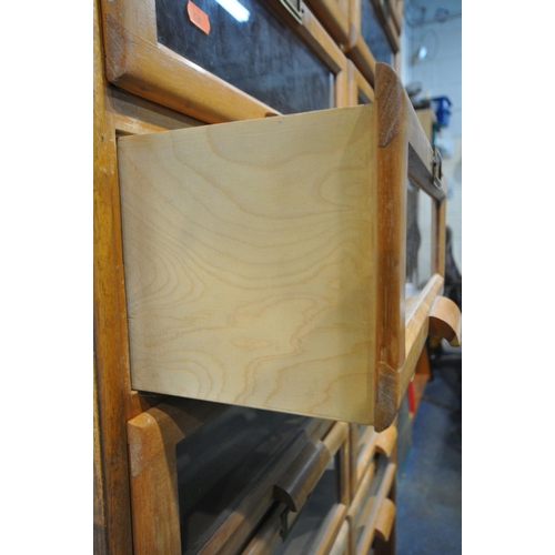 256 - A 20TH CENTURY OAK HABERDASHERY CABINET, fitted with sixteen glass fronted drawers, above a shelf, w... 