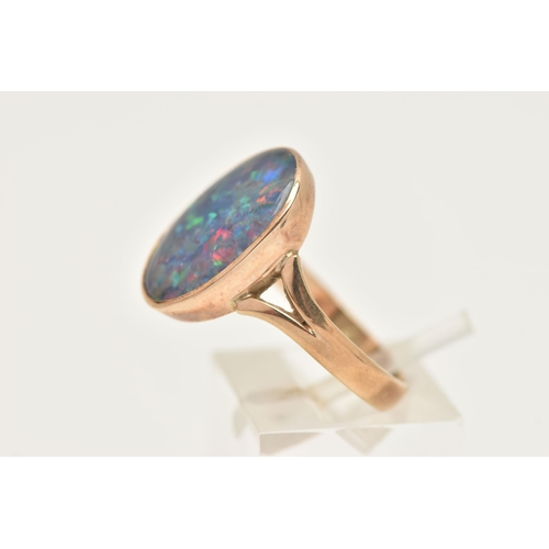 402 - A 9CT GOLD OPAL TRIPLET RING, of an oval form, collet set to the bifurcated shoulders and polished b... 