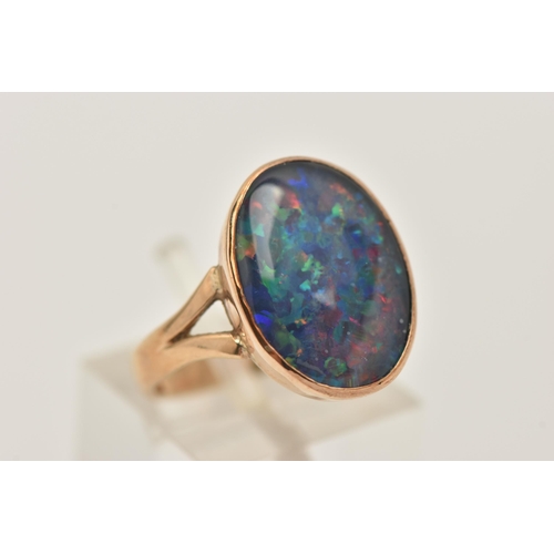 402 - A 9CT GOLD OPAL TRIPLET RING, of an oval form, collet set to the bifurcated shoulders and polished b... 