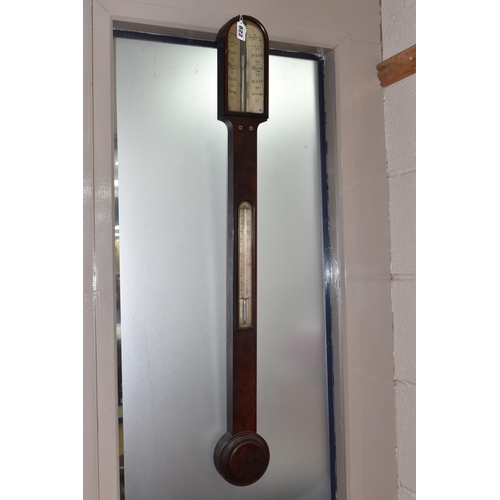 822 - A GEORGIAN CISTERN BAROMETER, in flame cut mahogany, the arched glass door enclosing a face signed '... 