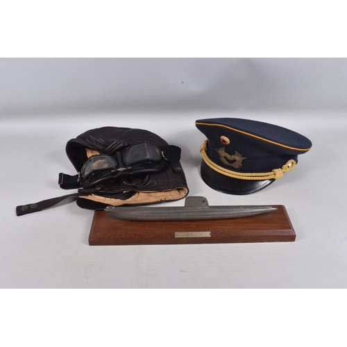 276 - A CAST MODEL OF A SUBMARINE ON A PLINTH AND OTHER MILITARY ITEMS, to include a 1980's German peaked ... 