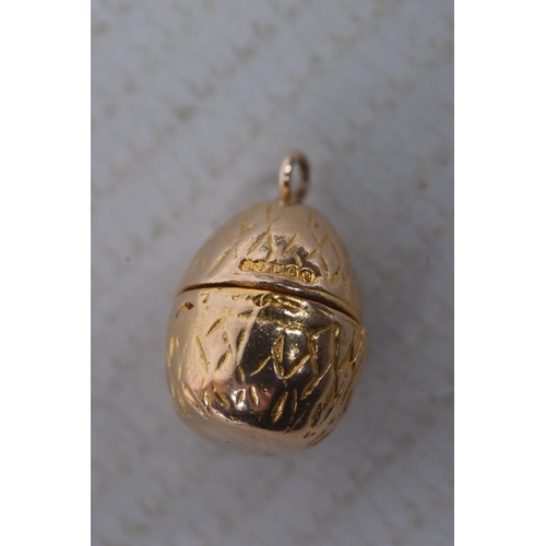 299 - A 9CT GOLD EGG AND CHICK CHARM, yellow gold egg with hinged fittings opening up to reveal an enamel ... 