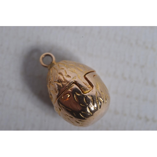 299 - A 9CT GOLD EGG AND CHICK CHARM, yellow gold egg with hinged fittings opening up to reveal an enamel ... 